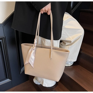 Detail of apricot pebbled leather tote bag with silk scarf on handle for commute