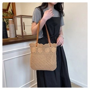 Detailed view of beige woven tote bag featuring hollow knit patterns and brown leather handles