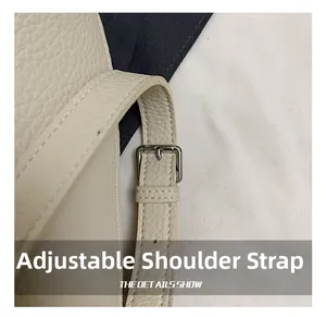 Macro detail of adjustable shoulder strap with silver buckle on cream leather bag