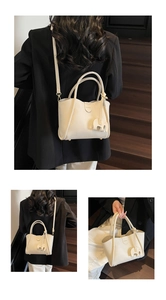 Details der cremefarbenen Beuteltasche mit Lederstruktur und Elefantenanhänger