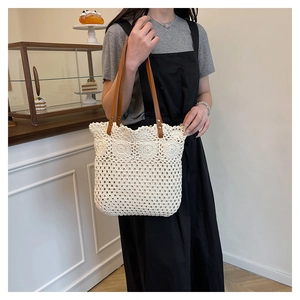 Detail view of hollowed floral knit pattern on off-white woven tote with leather handles