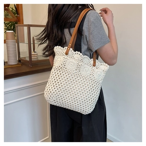 Close-up of crochet pattern and brown faux leather strap on beige woven tote bag