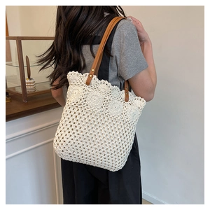 Detail of white crochet knit tote bag with boho floral patterns and leather shoulder strap