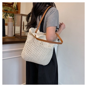 Detail of cream crochet tote bag with brown leather straps shown on shoulder