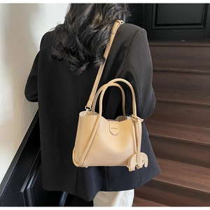 Detail der beigen Eimer-Handtasche aus genarbtem Leder mit Elefantenanhänger