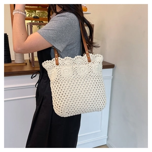 Detail of hollow-out woven tote bag featuring large floral pattern and brown leather strap