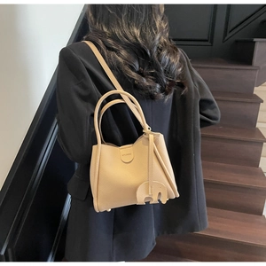 Detailansicht der beigen Eimer-Handtasche aus Narbenleder mit Elefanten-Anhänger