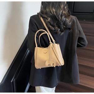 Detailansicht einer beige Beuteltasche mit Litschi-Struktur und Elefantenanhänger
