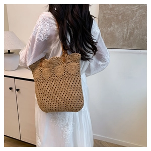 Detail of hand-woven hollow-out tote bag with brown leather strap in minimalist interior