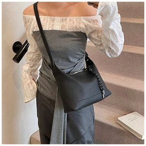 Close-up of black litchi grain leather crossbody bag with woven zipper pull details