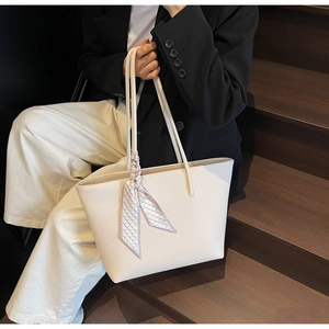Close-up of off-white tote bag with lychee texture leather and a plaid silk scarf detail