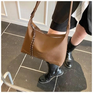 Close-up of brown lychee grain leather shoulder bag with woven zipper detail