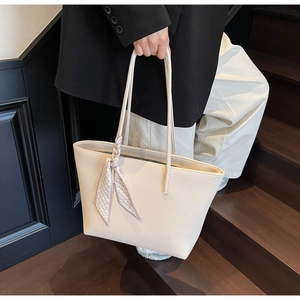 Close-up of cream textured leather tote bag with stylish checkered scarf on handle