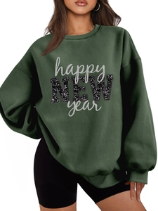 Detailaufnahme der Happy New Year Pailletten-Aufschrift auf dunkelgrünem Fleece-Sweatshirt