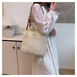 Close-up of cream crochet tote bag with brown leather handles and rivet details