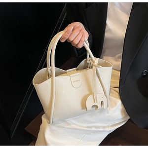 Detail der cremeweißen Handtasche aus Leder mit Litschi-Muster und Elefantenanhänger