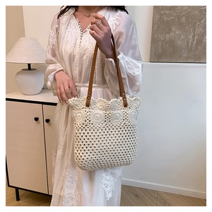 Detail of bohemian ivory crochet tote bag with brown leather strap and rivet texture