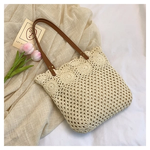 Detail of hollow woven tote bag with brown leather handle and rivet attachments