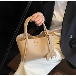 Detail der beigen Beuteltasche mit Litschi-Lederstruktur und Elefanten-Anhänger