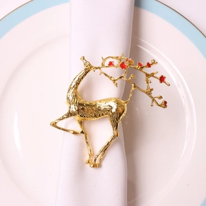 Rond de serviette en forme de renne doré avec fleurs rouges sur une table dressée