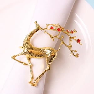 Rond de serviette renne doré avec détails en émail rouge sur nappe blanche