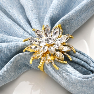 Detailed close-up of a golden floral napkin ring with sparkling rhinestones on blue fabric