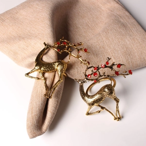 Détail de ronds de serviette cerf doré avec fleurs rouges sur lin beige clair