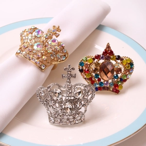 Detailed close-up of crown-shaped napkin rings with colorful rhinestones on a white plate