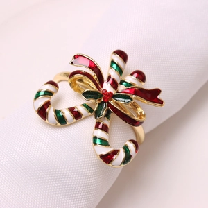 Christmas candy cane napkin ring with red bow and holly leaves on a white linen napkin