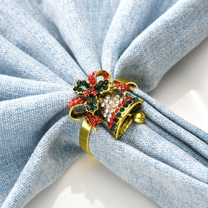 Detail of Christmas napkin ring with golden bells, red and green rhinestones on linen