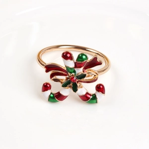 Close-up of candy cane napkin ring with red bow and rhinestone on a white plate