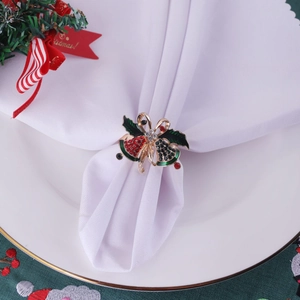 Christmas napkin ring with gold bell, green leaves and red rhinestones on white cloth
