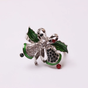 Close-up of Christmas bell napkin ring with green holly leaves and sparkling rhinestones