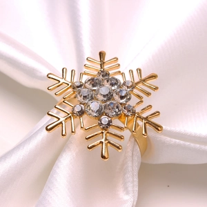 Classic golden snowflake napkin ring with sparkling rhinestones on white satin fabric