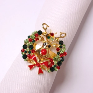 Close-up of golden reindeer napkin ring with rhinestones and a red bow tie on white linen