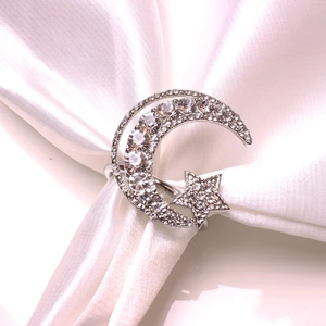 Detailed view of moon and star napkin ring with crystals on white silk fabric