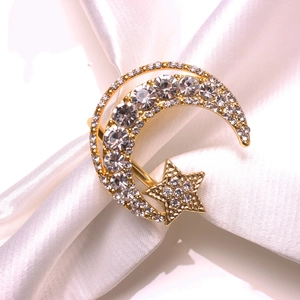 Elegant gold star and crescent moon napkin ring with clear crystals on white silk fabric