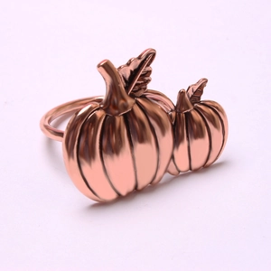 Detailed macro view of rose gold pumpkin napkin rings with textured leaf accents