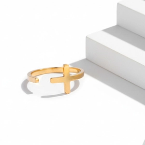 Detailed view of an 18K gold plated stainless steel adjustable cross ring on white podium