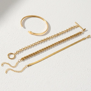 Detail of four-piece gold stainless steel set including snake bangle and OT buckle chains