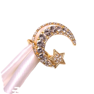 Elegant gold star and moon napkin ring with pavé rhinestones on white satin fabric