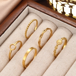 Detail of five gold geometric stainless steel rings displayed in a luxury velvet jewelry box