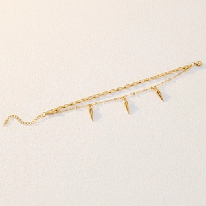 Détail d'un bracelet double couche doré orné de pendentifs à pointes coniques