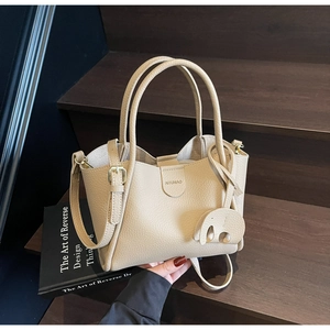 Detail der beigen Beuteltasche mit Litschi-Lederstruktur und Elefanten-Anhänger