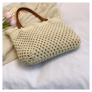 Close-up of cream hollow woven tote bag with brown leather handles and chic floral crochet