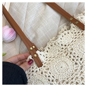 Detail of woven cotton tote bag showing hollow-out pattern and brown leather handle