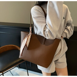 Detail of large brown tote bag in pebbled leather with a stylish printed silk scarf