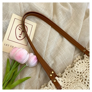 Detail of crochet cotton tote with brown leather strap and gold rivet accents