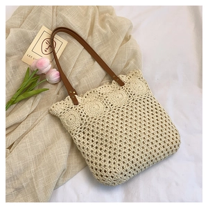 Detail of hollow-out crochet pattern on cream tote bag with brown leather straps