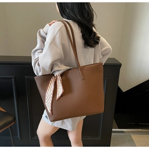 Brown textured tote bag with silk scarf accessory shown on shoulder for daily commute